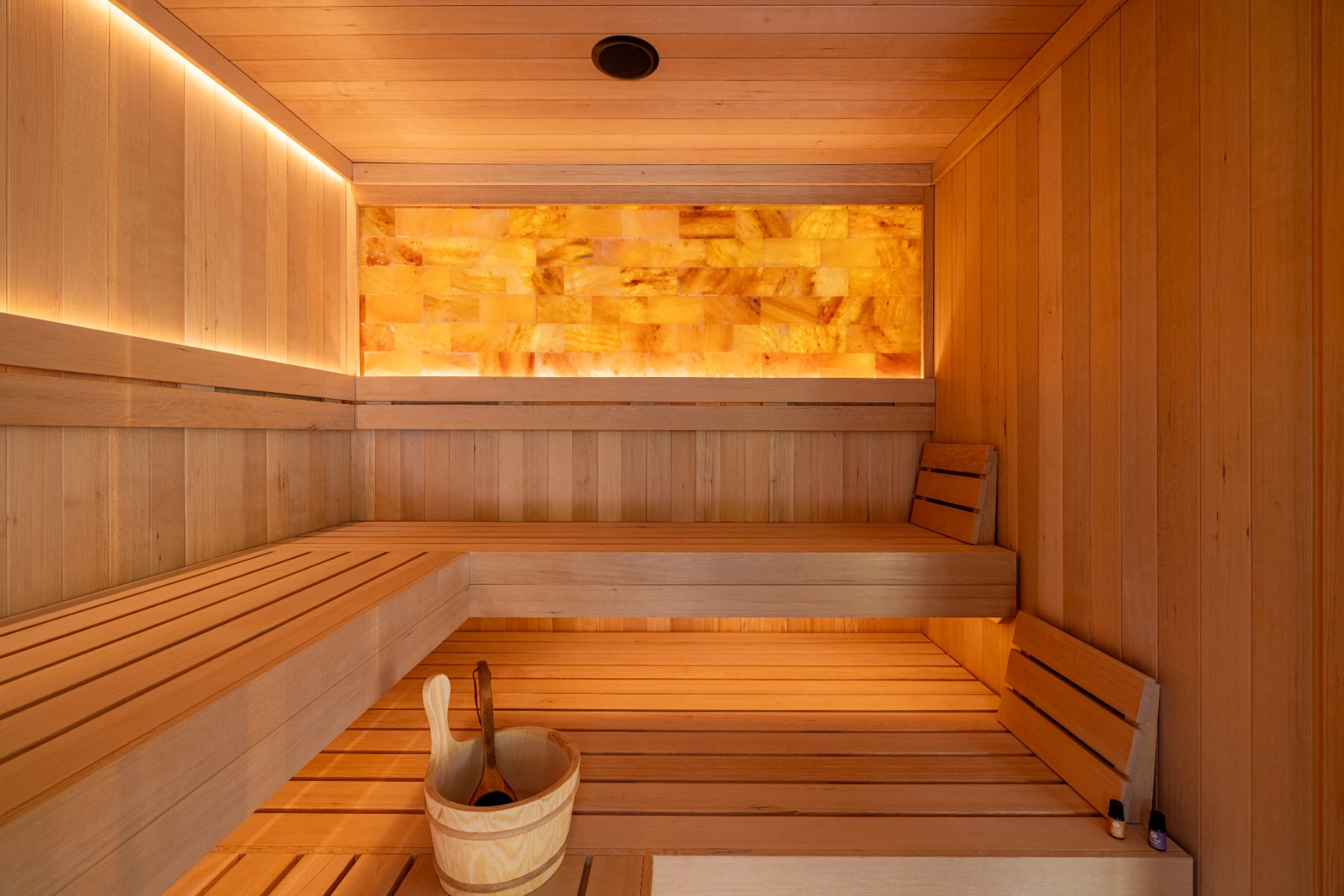 Modern sauna bench in front of illuminated Himalayan salt wall