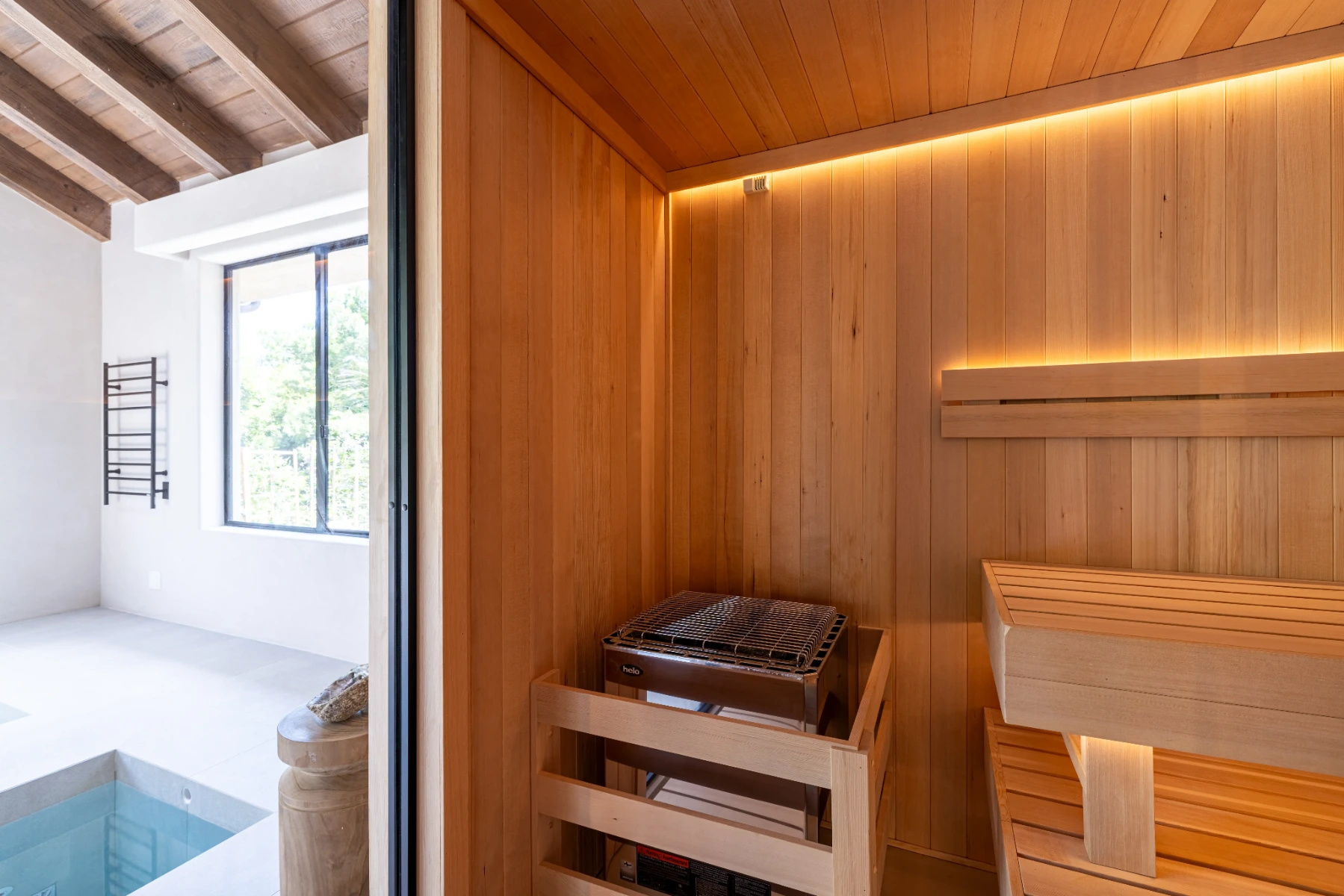 View from inside a custom cedar sauna overlooking an adjacent indoor cold plunge, designed to make contrast therapy convenient and enjoyable at home.