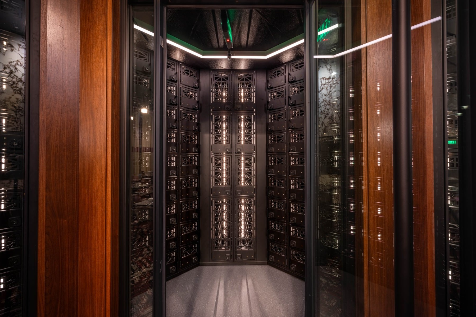 Full-length glass wine display at Ocean 48 with label-forward racking, matte black framing, and elegant backlighting.