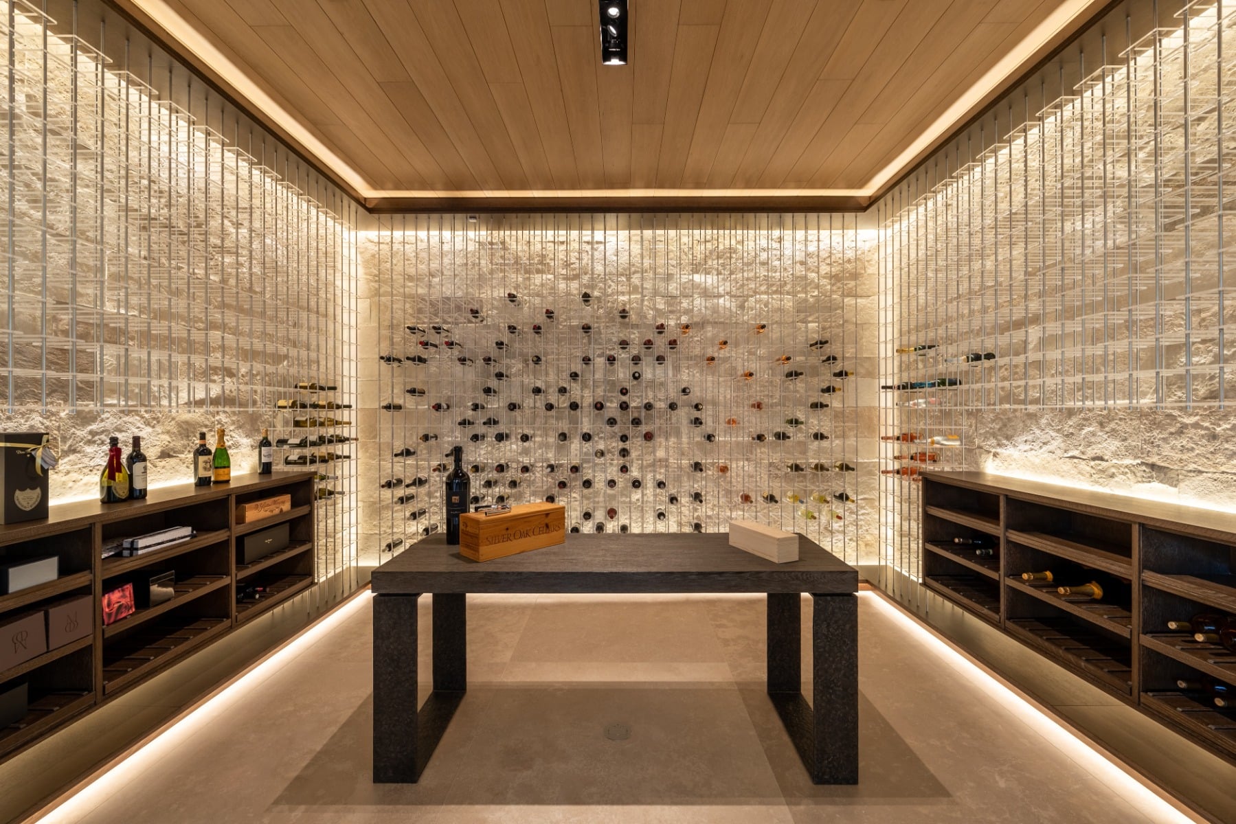 Modern wine wall in Newport Beach with glass enclosure, LED backlighting, black framing, and ocean-view living space.