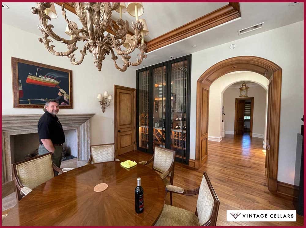 Jason, Expert Designer at Vintage Cellars Poses along with the Elegant Glass Wine Room in Phoenix